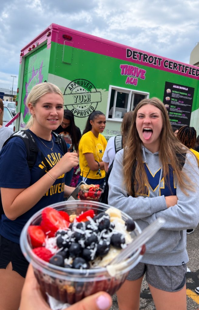 Guests enjoy fruit-topped acai bowls beside the green Thrive food truck.